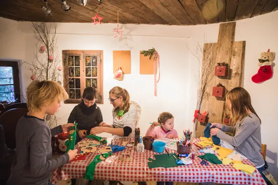 Children crafting Christmas decorations at a table with festive supplies